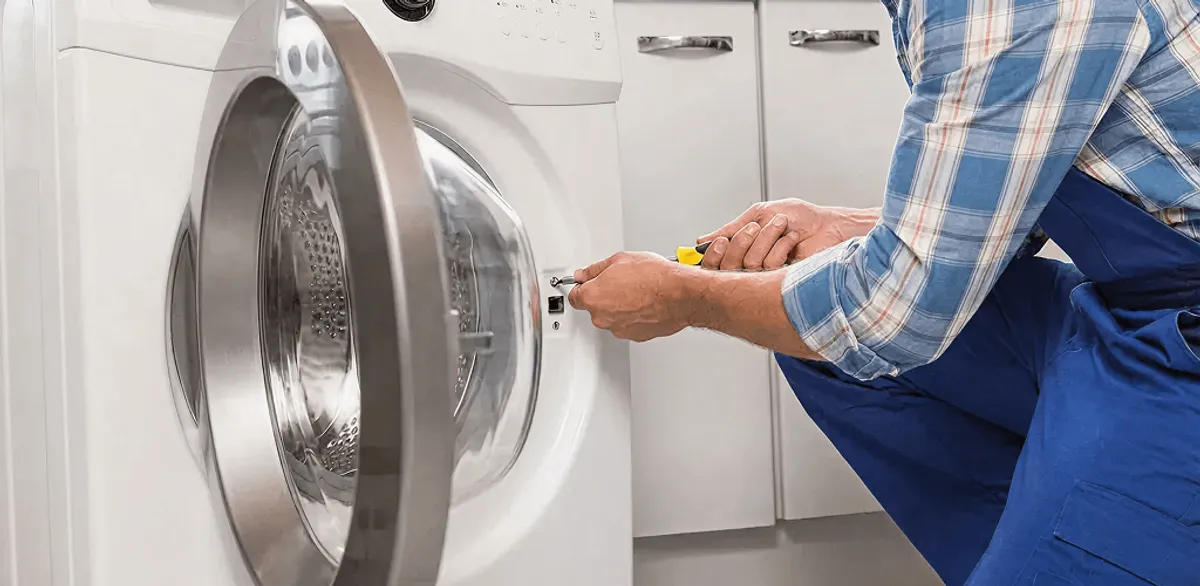 Handyman repairing a clothes dryer and checking electrical connections in Gilbert, AZ