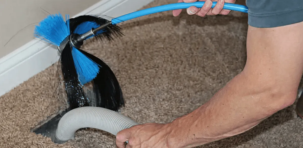 Dryer vent cleaning technician brushing lint from a vent line in Gilbert, AZ