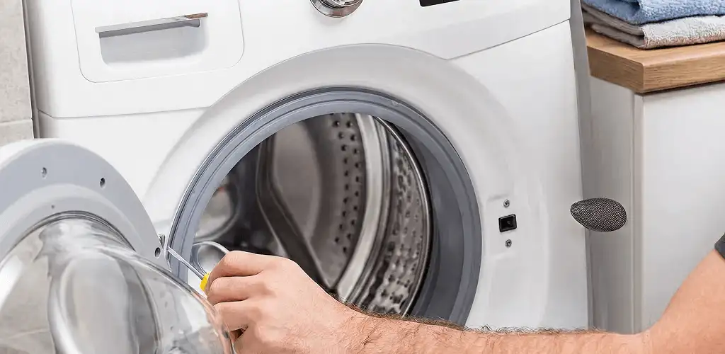Handyman repairing a front-load washing machine and inspecting the drum in Gilbert, AZ